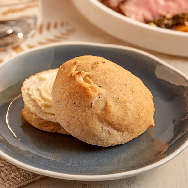 An OMG Gluten Free white dinner roll with butter on a plate.