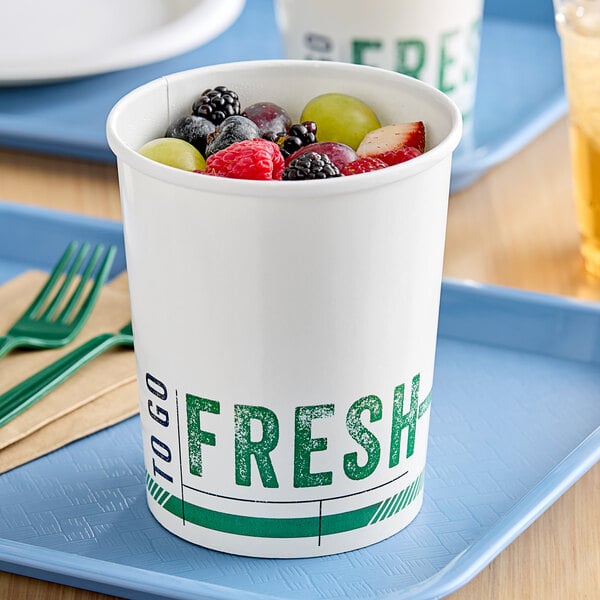 A white paper bowl with the words "To Go Fresh" filled with fruit on a white tray.