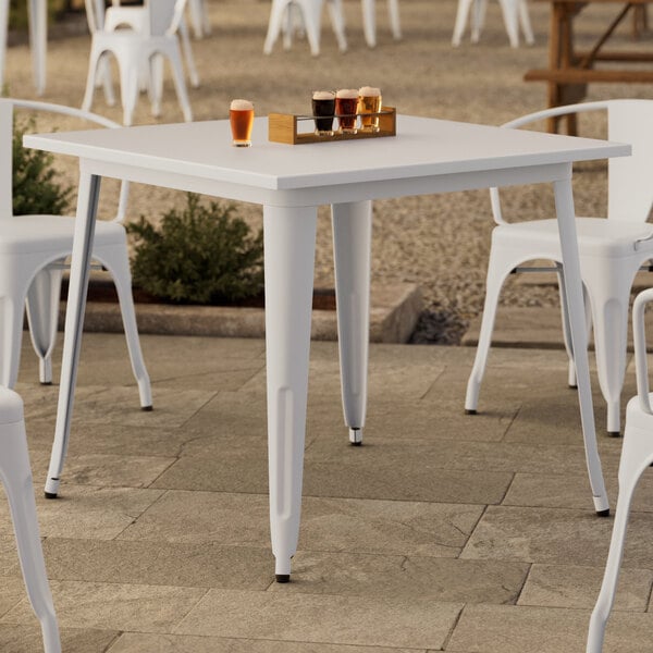 A Lancaster Table & Seating outdoor table with white legs.