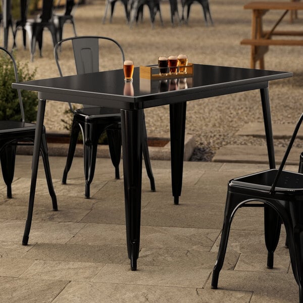 A black Lancaster Table & Seating outdoor table with chairs on a patio.