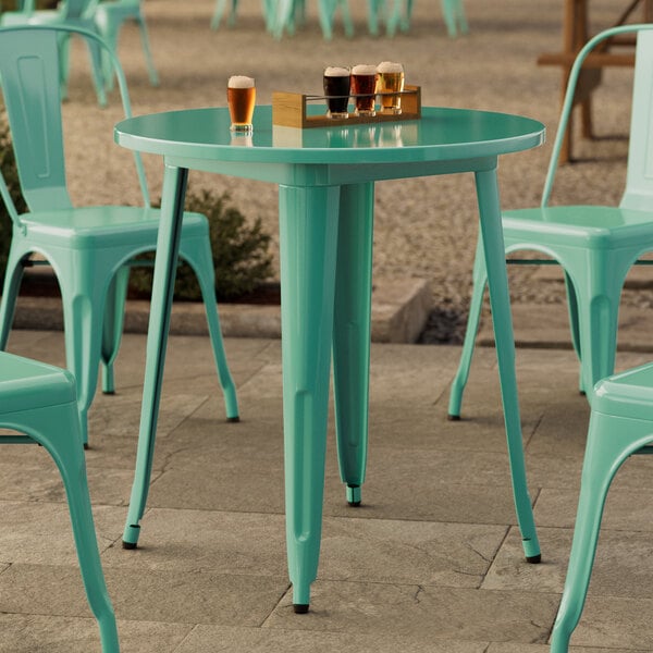 A Lancaster Table & Seating aquamarine outdoor table with chairs on a patio.