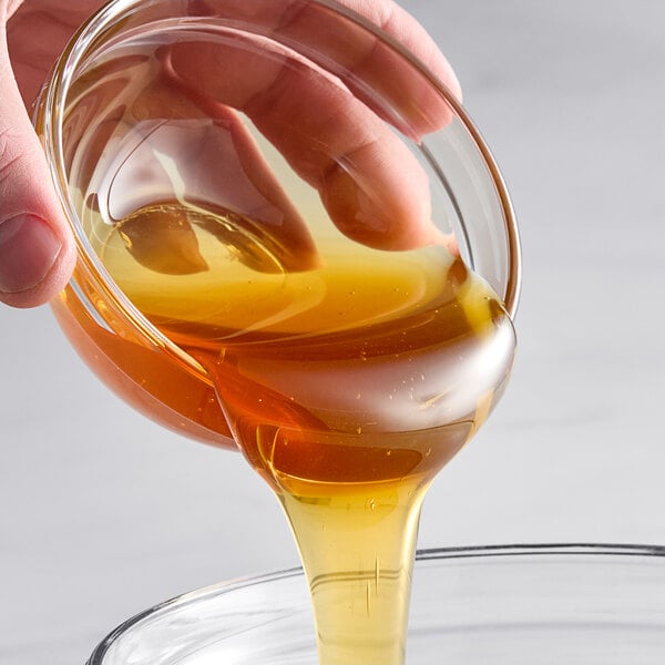 A person pouring Hometown Provisions Baker's Special Honey into a glass bowl.