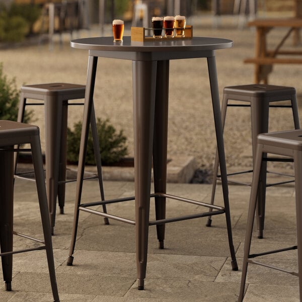 A Lancaster Table & Seating Alloy Series round copper bar height table with several glasses of beer on it.