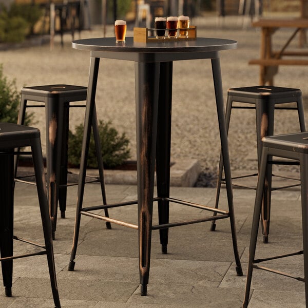 A Lancaster Table & Seating distressed copper bar height outdoor table with four stools on a patio.