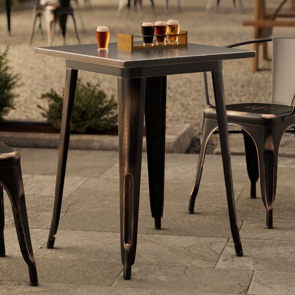 A Lancaster Table & Seating distressed copper outdoor table with drinks on it.