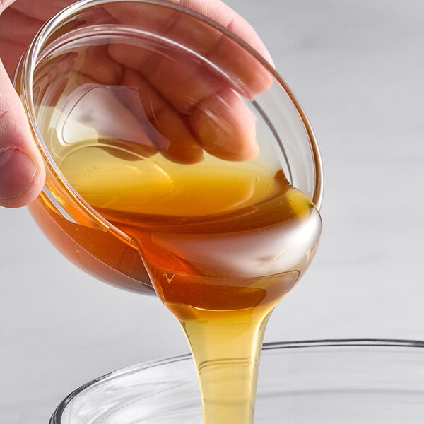 A hand pouring Hometown Provisions Clover Honey into a glass bowl.