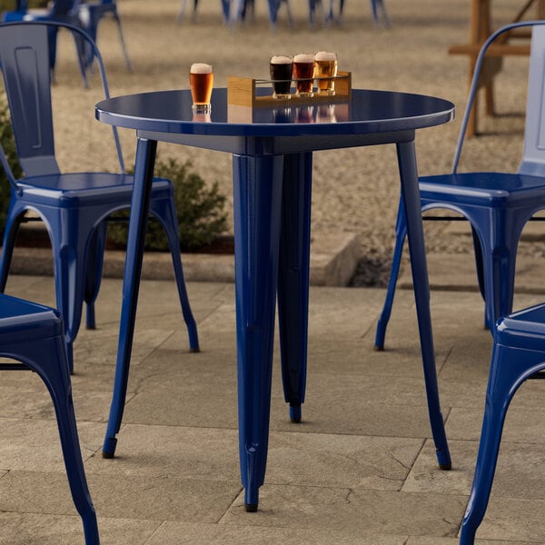 A Lancaster Table & Seating round blue metal table and chairs on a stone patio.