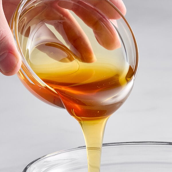 A hand pouring Hometown Provisions Buckwheat Honey into a glass bowl.