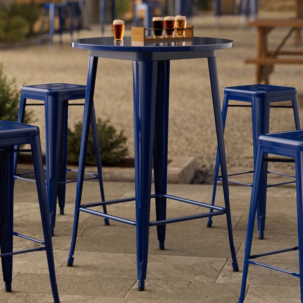 A blue Lancaster Table & Seating bar table with blue chairs on an outdoor patio.