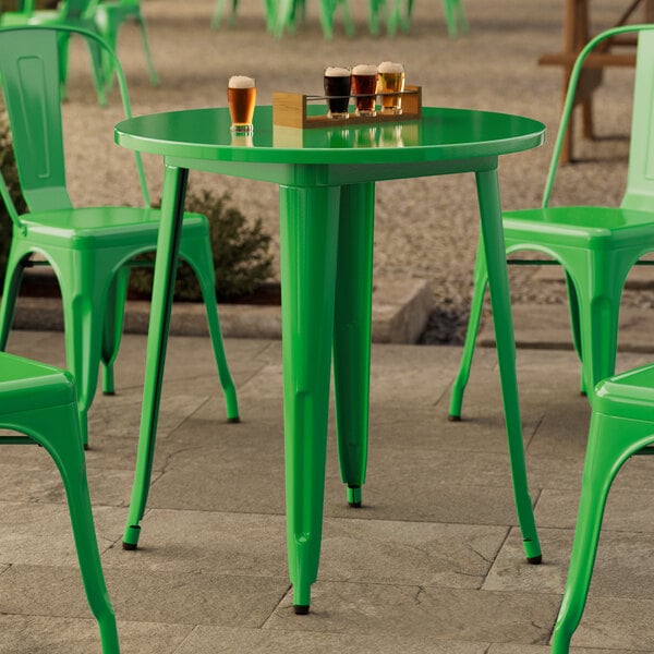 A Lancaster Table & Seating jade green table and chairs on a stone patio with glasses of beer on the table.