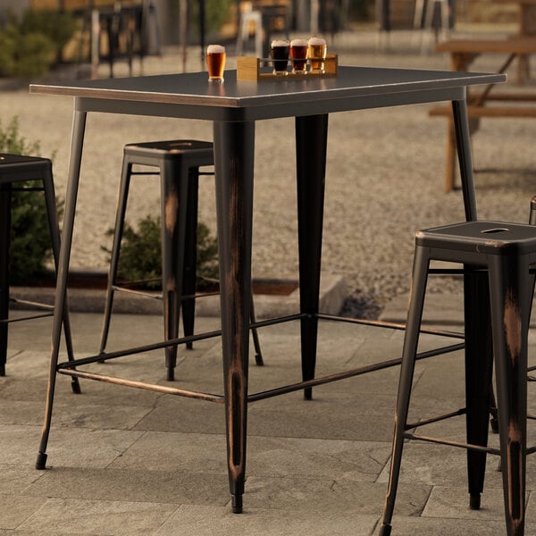 A Lancaster Table & Seating distressed copper bar table with drinks on it outside.