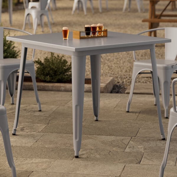 A Lancaster Table & Seating nickel gray outdoor table with glasses of beer on it.