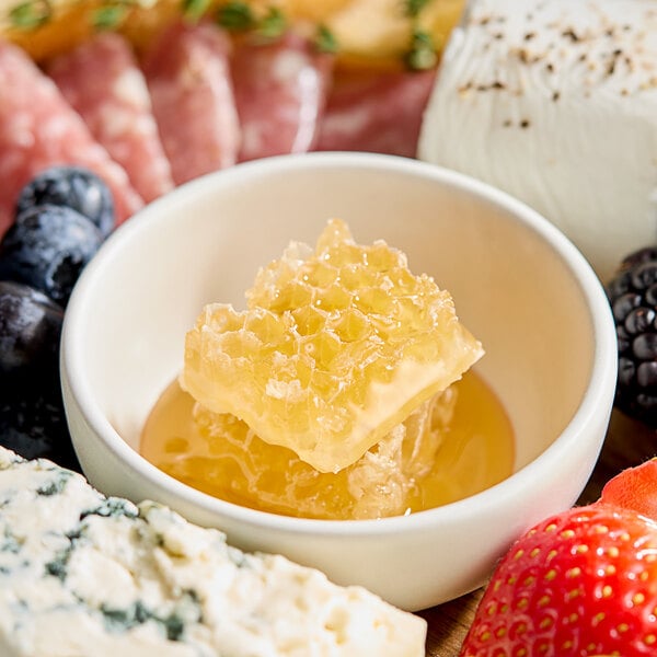 A bowl of Hometown Provisions honeycomb with fruit on a table.