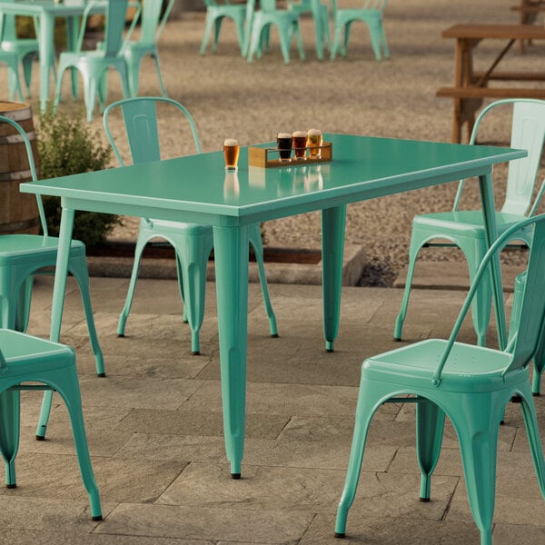 A Lancaster Table & Seating aquamarine table with green chairs on an outdoor patio.