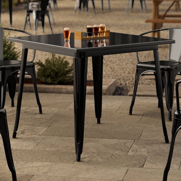 A Lancaster Table & Seating black table and chairs on an outdoor patio.