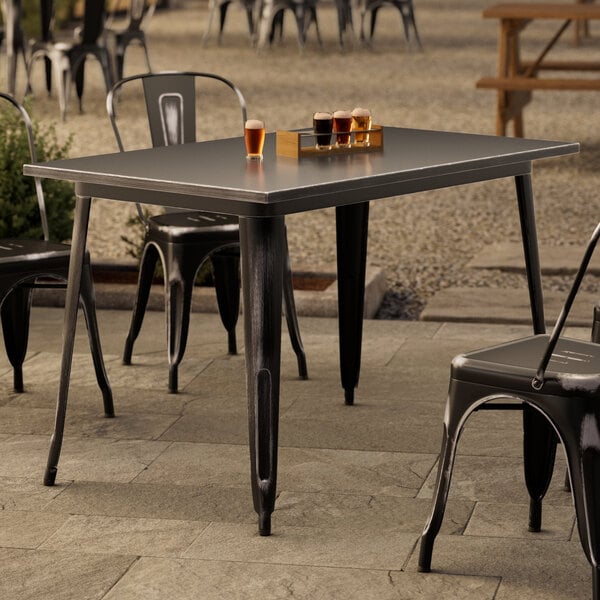 A Lancaster Table and Chairs on an outdoor patio with glasses of beer.