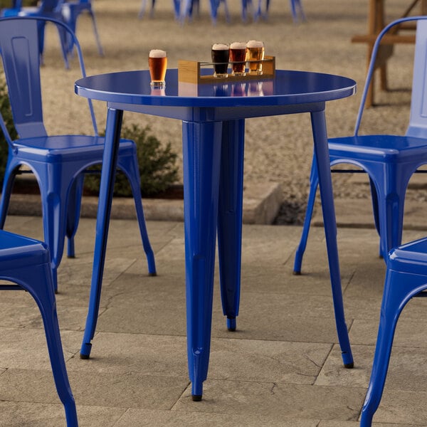 A Lancaster Table & Seating blue metal table with legs on an outdoor patio.