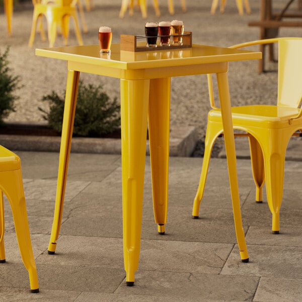 A Lancaster Table & Seating citrine yellow outdoor table on a patio.