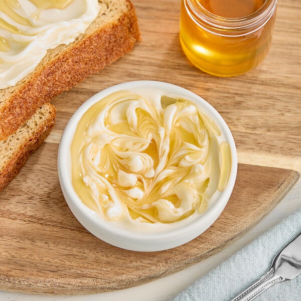 A bowl of butter and bread next to a jar of Hometown Provisions Alfalfa Honey.