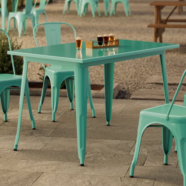 A Lancaster Table & Seating Aquamarine outdoor table with chairs on a patio.