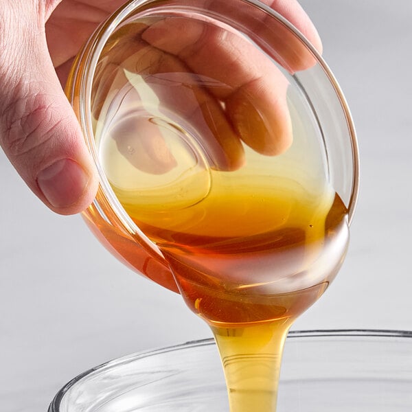 A hand pouring Hometown Provisions Orange Blossom Honey into a glass bowl.