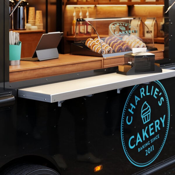 A Regency aluminum folding concession shelf attached to the side of a food truck.