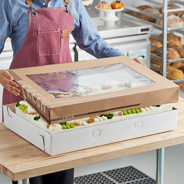 A woman holding an Innopak To Go Fresh Kraft bakery box full of food.