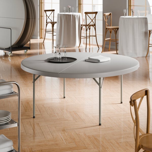 A large round gray folding table with gray legs, set up in a banquet or event space.