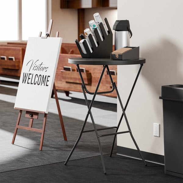 A round black bar height plastic folding table with black legs.