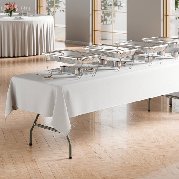 A large rectangular gray heavy-duty blow molded plastic folding table with gray legs, set up for a buffet with chafing dishes and a white tablecloth.
