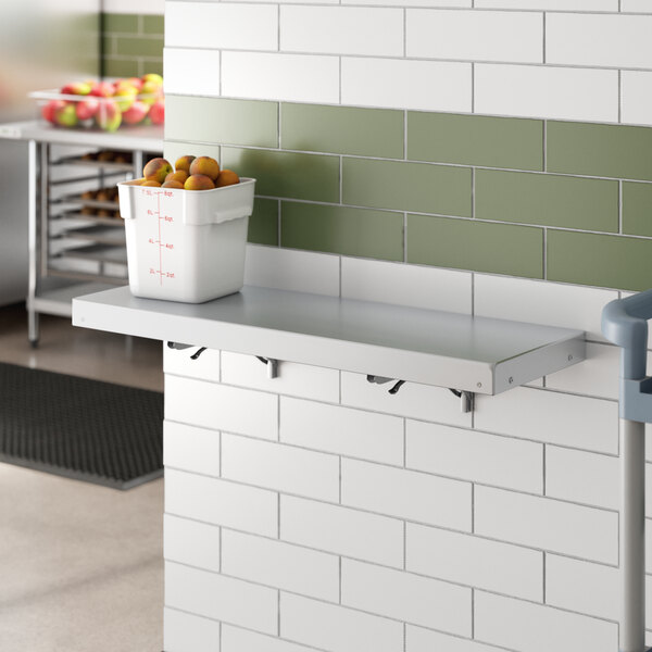 A Regency aluminum folding shelf holding a white bucket of fruit.