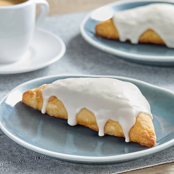 A pastry with white frosting on a plate next to a bottle of Hometown Provisions Gourmet Pure Vanilla Extract.