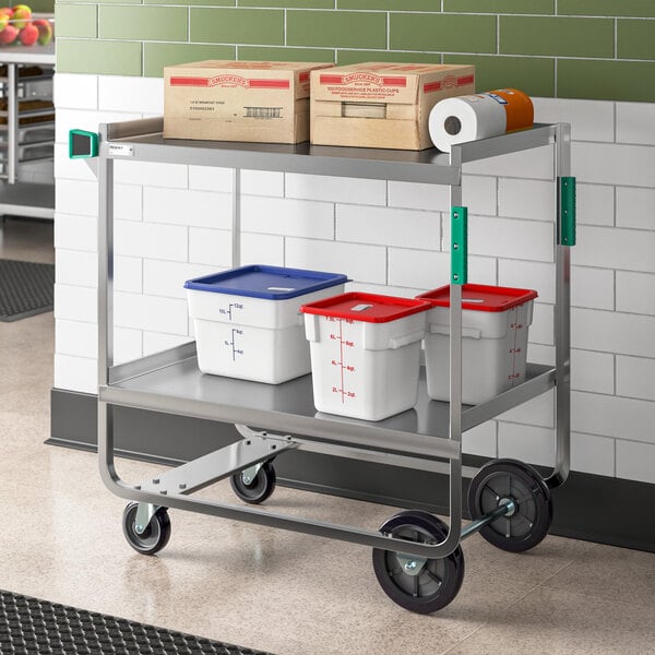 A Regency stainless steel utility cart with two shelves holding white and blue plastic containers.