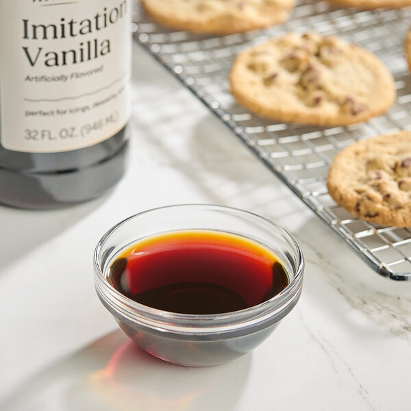 A close up of a bottle of brown liquid next to cookies.