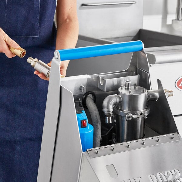 A woman using a Shortening Shuttle machine to transport waste oil from a fryer.
