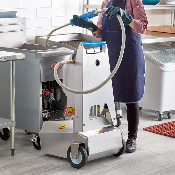 A woman in a blue apron using a Shortening Shuttle machine to transport waste oil.