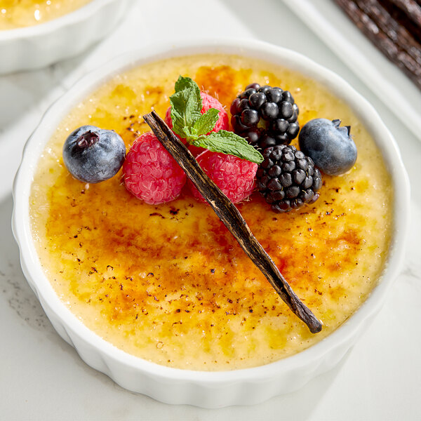 A dessert with berries and vanilla sticks served in a bowl.