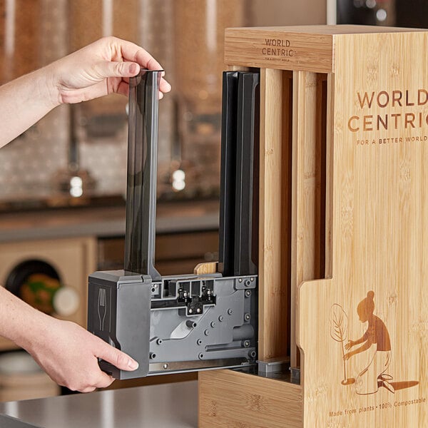 A person holding a World Centric Touchless Cutlery Dispenser.