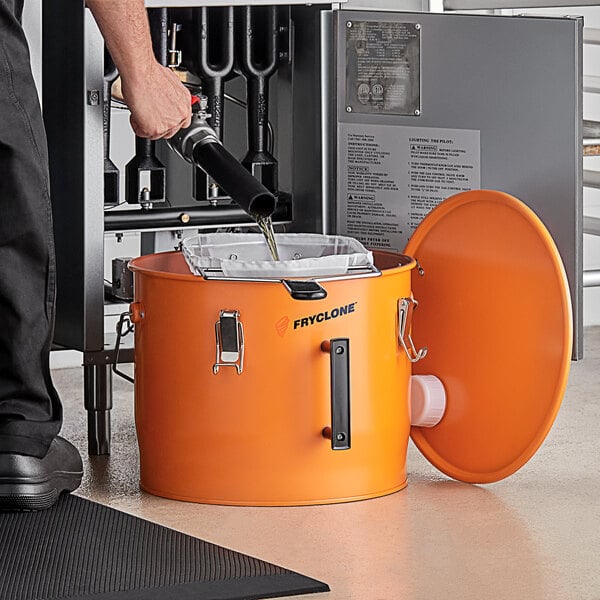 A man uses a Fryclone oil filter bag holder to pour liquid into an orange bucket.