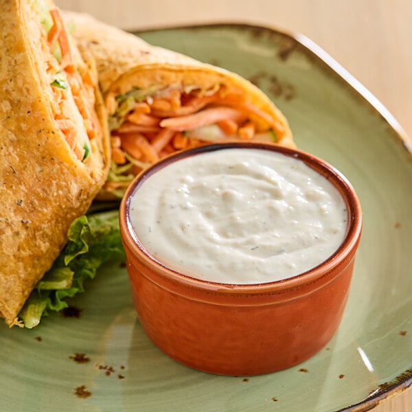 A tortilla wrap with a side of white JUST Ranch dressing on a plate.