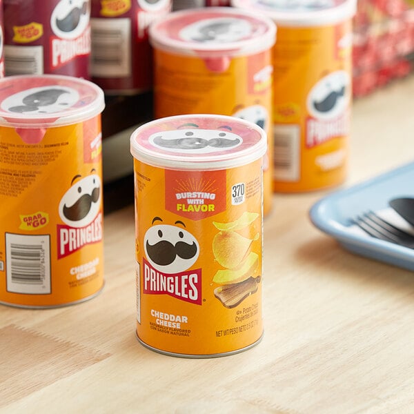 A table with a group of Pringles Cheddar Cheese potato chip containers.