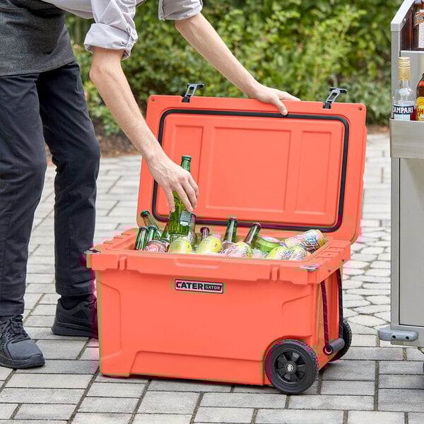 A man using a CaterGator outdoor cooler to chill drinks at an outdoor event.