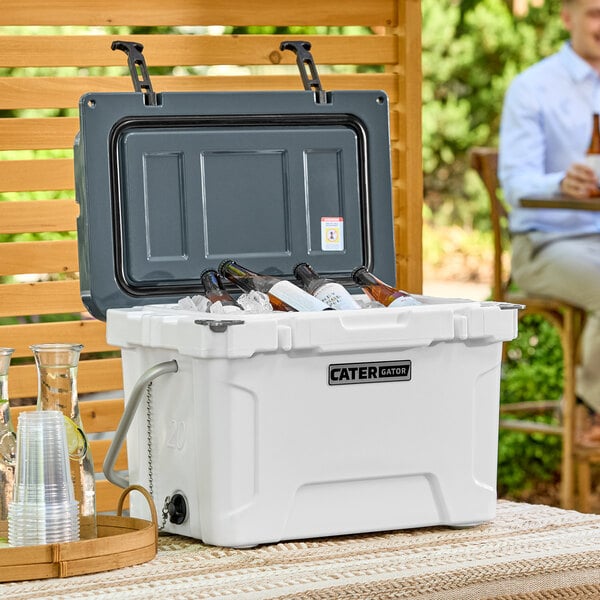 A man sits on a patio with a CaterGator outdoor cooler on the table.