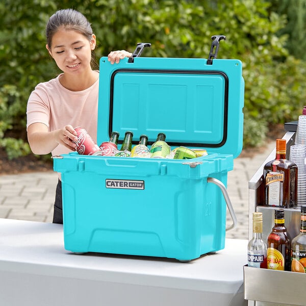A woman opening a CaterGator outdoor cooler to put drinks inside.