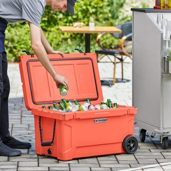 A man putting a can into a CaterGator outdoor cooler.