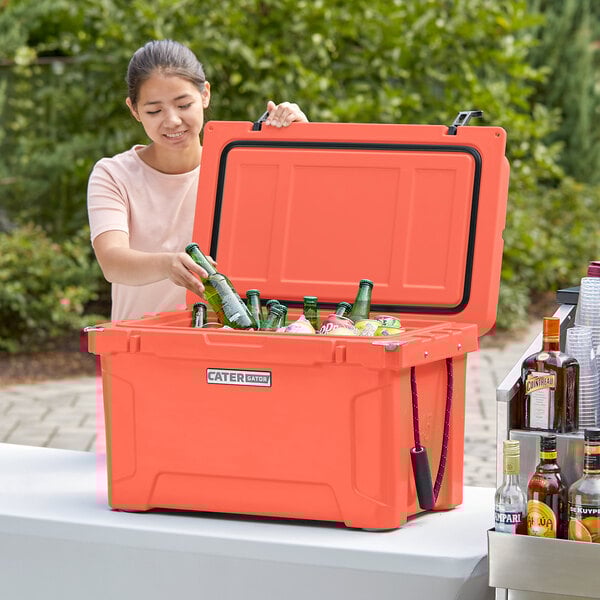 A woman using a CaterGator outdoor cooler to hold bottles of beer.