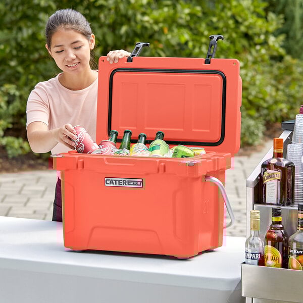 A woman opening a CaterGator outdoor cooler to put a drink inside.