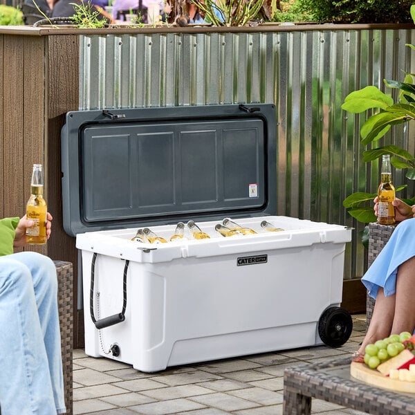 A couple sitting outside by a CaterGator outdoor cooler on a table.