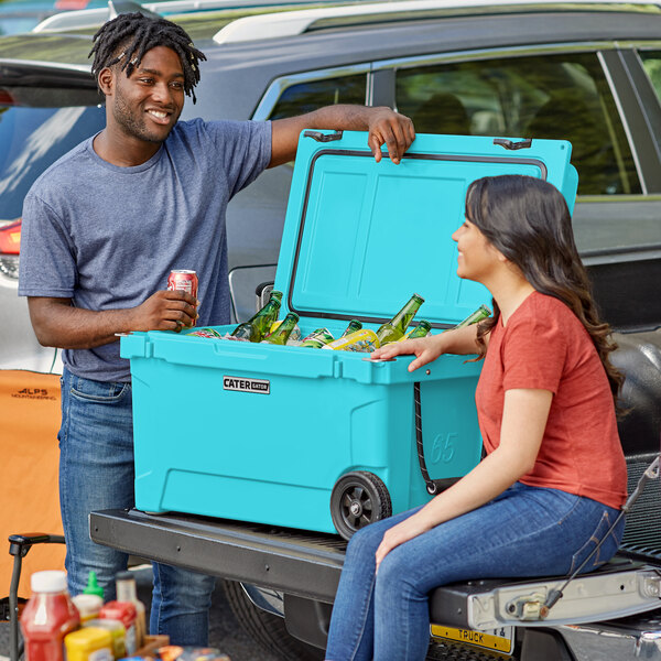 A man and woman sitting on the back of a CaterGator cooler.