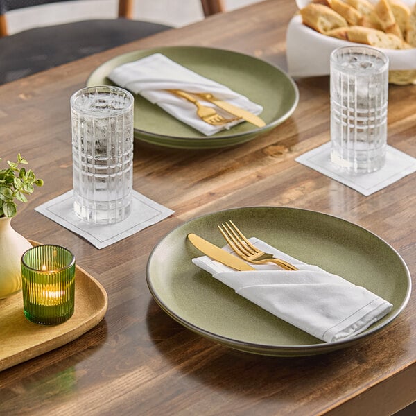 A white single-use cotton beverage napkin placed under a glass of water on a dining table.